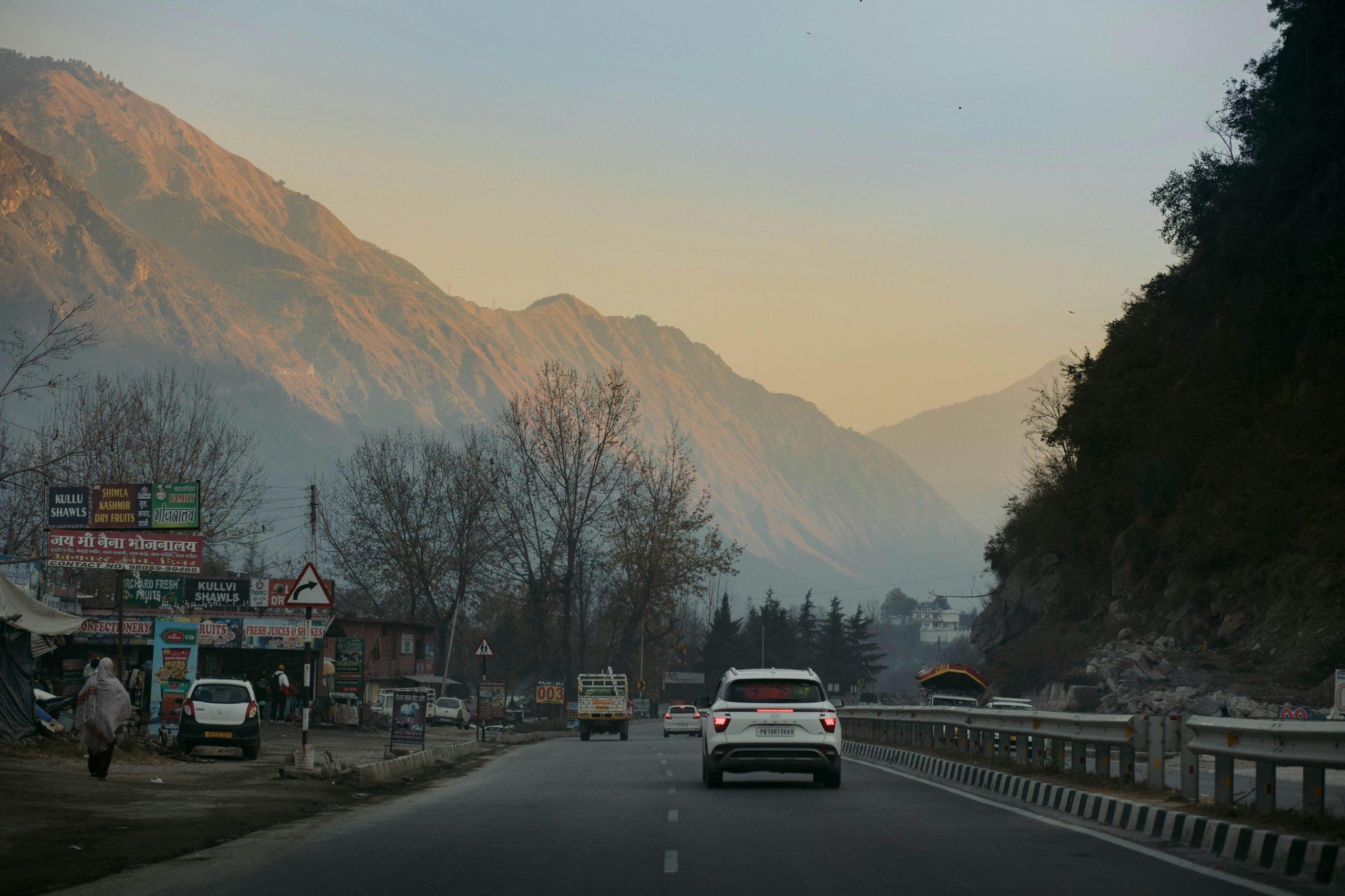 Captivating view of a highway through Kasol, Himachal Pradesh, with mountains at sunset.